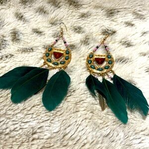 Gold bejeweled dangle earrings with green feathers